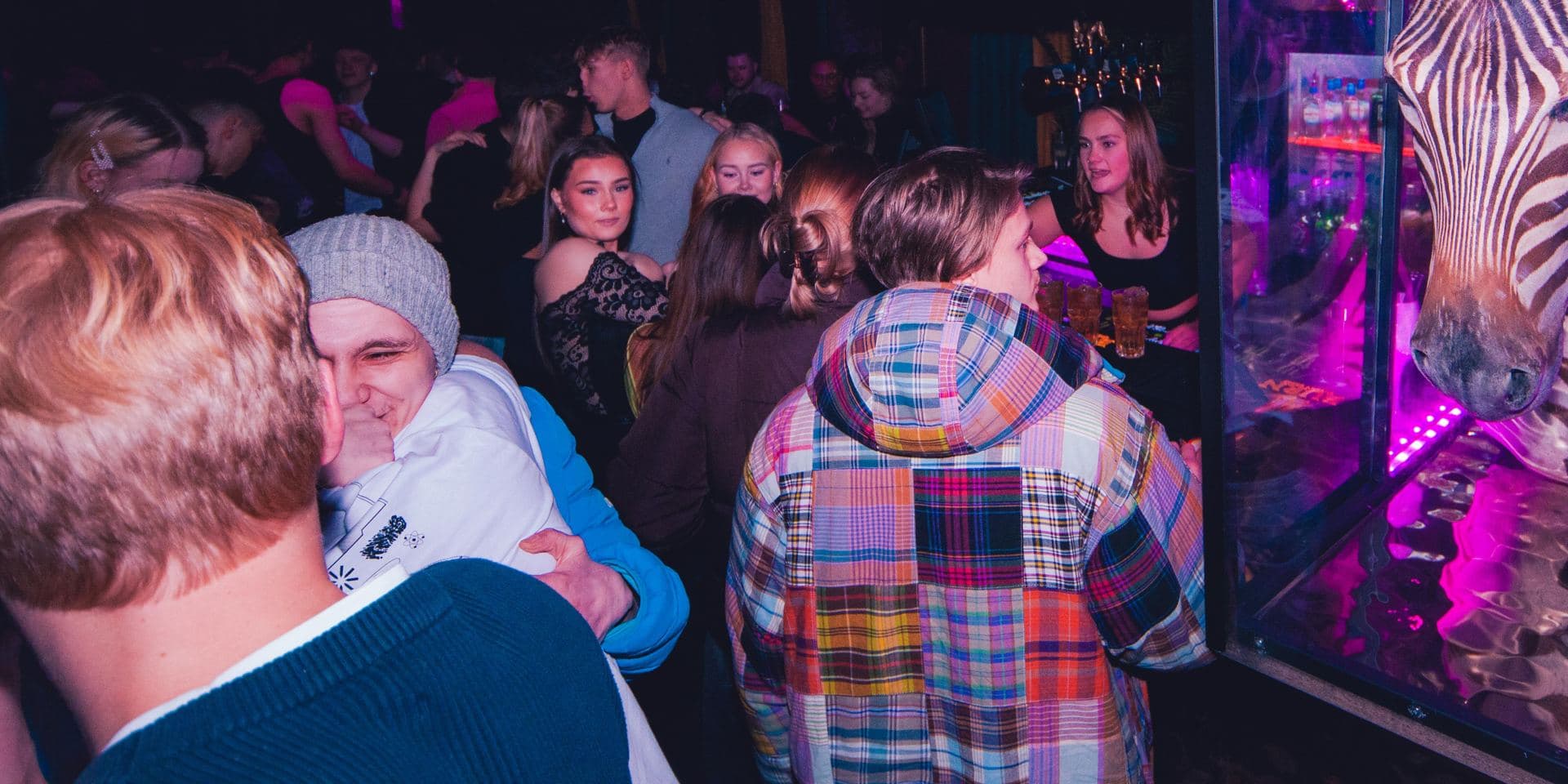 Gjester ved baren på SKINS med sebraen i glassmonteren
